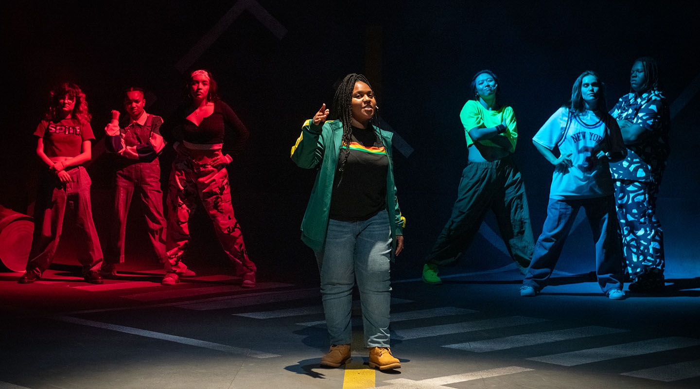 students in hip-hop clothing stand in a formation on the Keck Theater stage