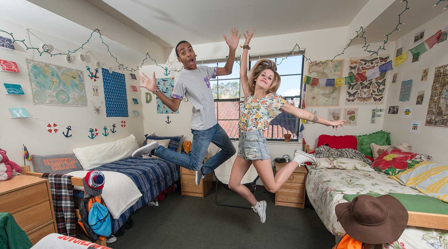 Two students dancing playfully in a dorm room