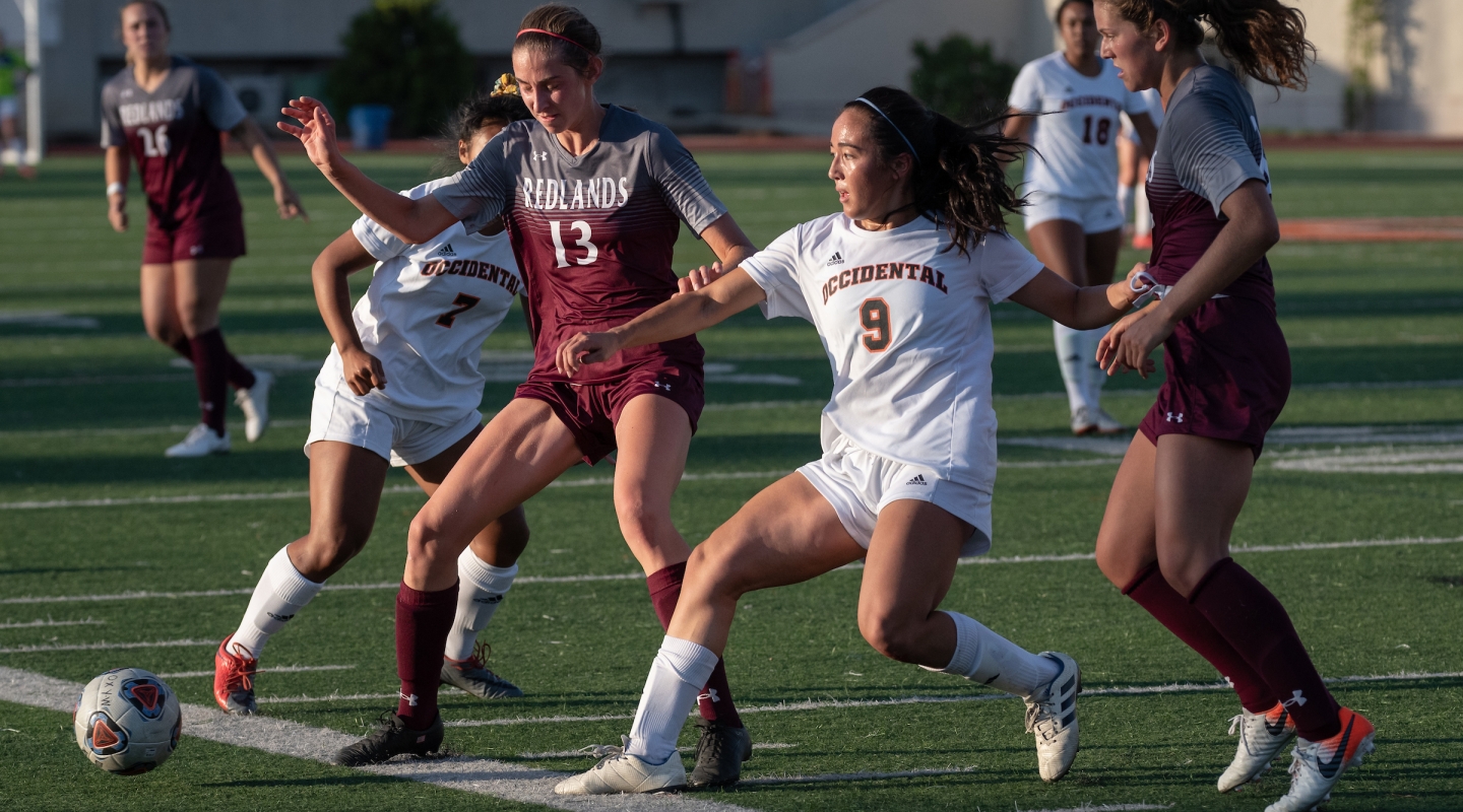 Four women playing soccer on turf field during daylight