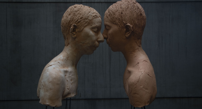 color image of two sculptural busts in profile, with faces touching
