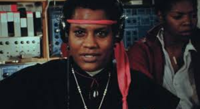 Grainy photo of a person looking straight into the camera wearing a red headband. 