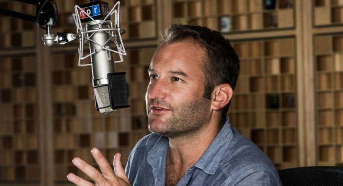 Journalist David Greene in a blue shirt talking into a radio mic