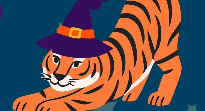 a tiger stretching out with a witch's Halloween hat