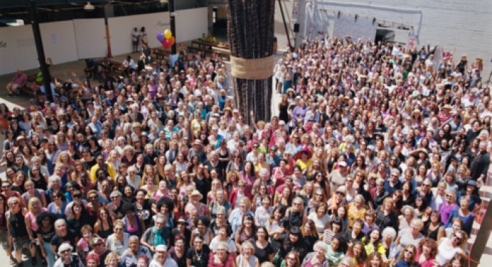 A large crowd of people standing together around an art sculpture