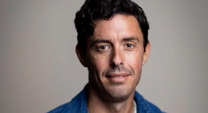 podcaster Tim Miller in a blue shirt with short dark hair looking at the camera