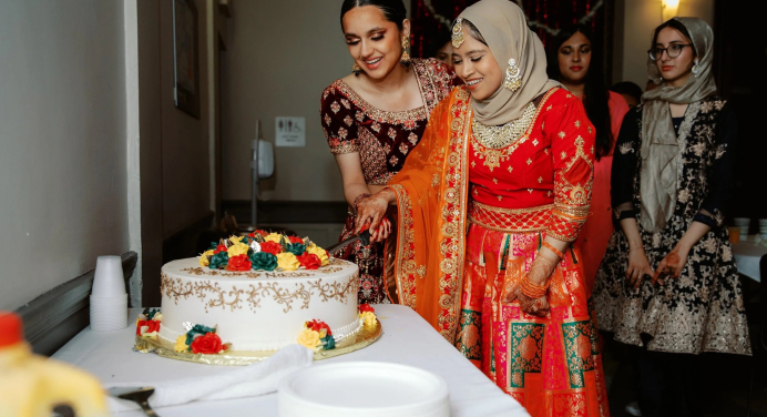 Image of two people cutting cake at a Mock Shaadi (Wedding)