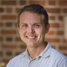 Dustin Madison headshot in front of brick wall