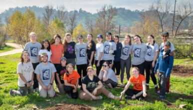 a group of Oxy students stand outdoors in a grassy field after volunteering