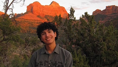 Emri Espinoza headshot with alpineglowing desert mountains in the background
