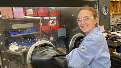 Occidental College student Kelsey Hertz in a science lab with a lab coat and goggles