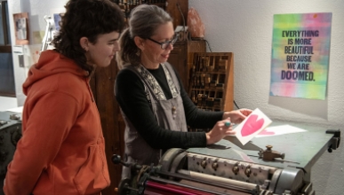 An Occidental College professor and student using a letterpress printing machine