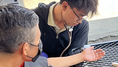Occidental College student Tylor Lee taking a patient's blood pressure reading