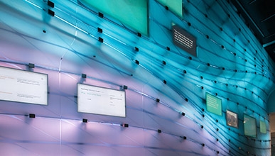 The media wall in Johnson Hall glows blue, turquoise, and purple