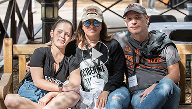 Oxy student sits on bench with parents wearing Oxy gear