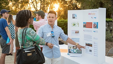 Student gestures to presentation board as he explains InternLA experience