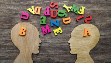 two wooden head cutouts and colored jumbled letters representing different individuals attempting to communicate