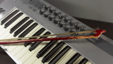 an electronic keyboard controller with a violin bow resting on its keys