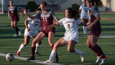 Four women playing soccer on turf field during daylight