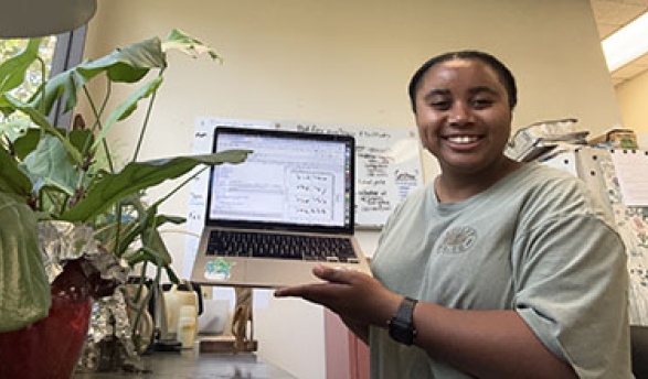 a young woman holding up her laptop and smiling