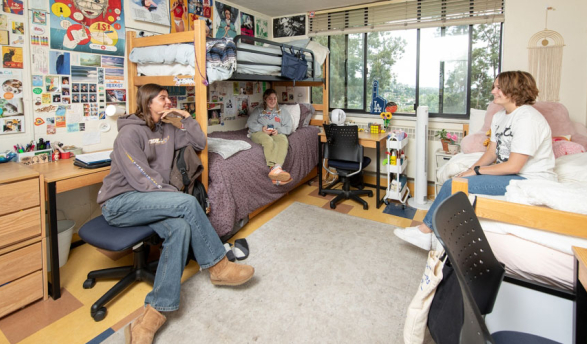 students hanging out on chairs in their dorm room, talking