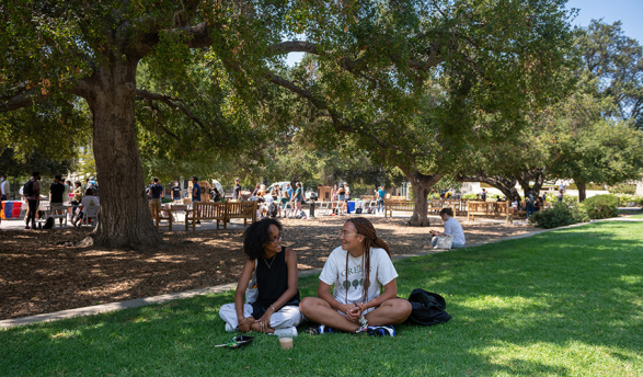 Two students sitting on the lawn of the Quad