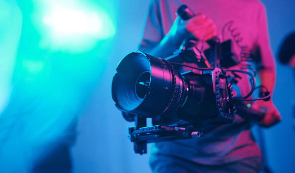 a cameraman holding a film camera with a colored background