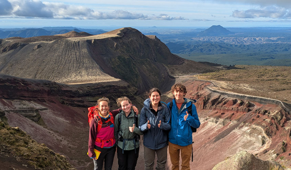 Four Occidental researches posing on top of a mountain peak in New Zealand