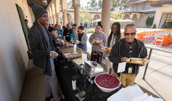 Occidental College staff members lined up at a buffet line, getting food