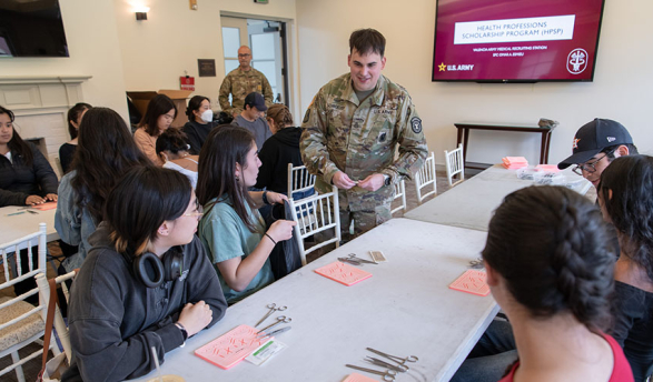 A US Army personnel teaching students about how to perform medical sutures using test kits