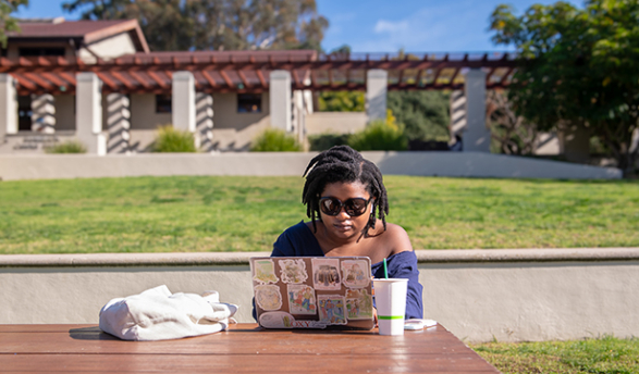 An Occidental student works on a laptop outside of the Tiger Cooler