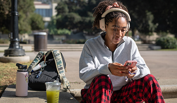 An Occidental student checks her phone while sitting on the quad on the Los Angeles campus.