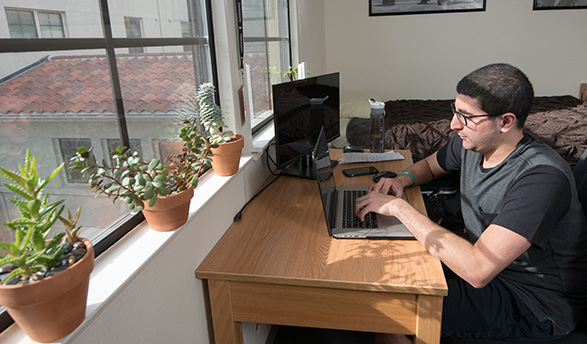 An Occidental student studies at the desk in his room