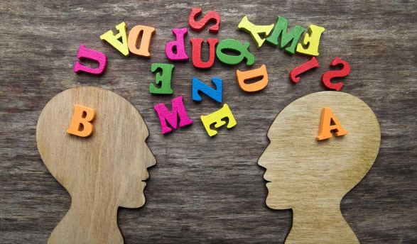 two wooden head cutouts and colored jumbled letters representing different individuals attempting to communicate