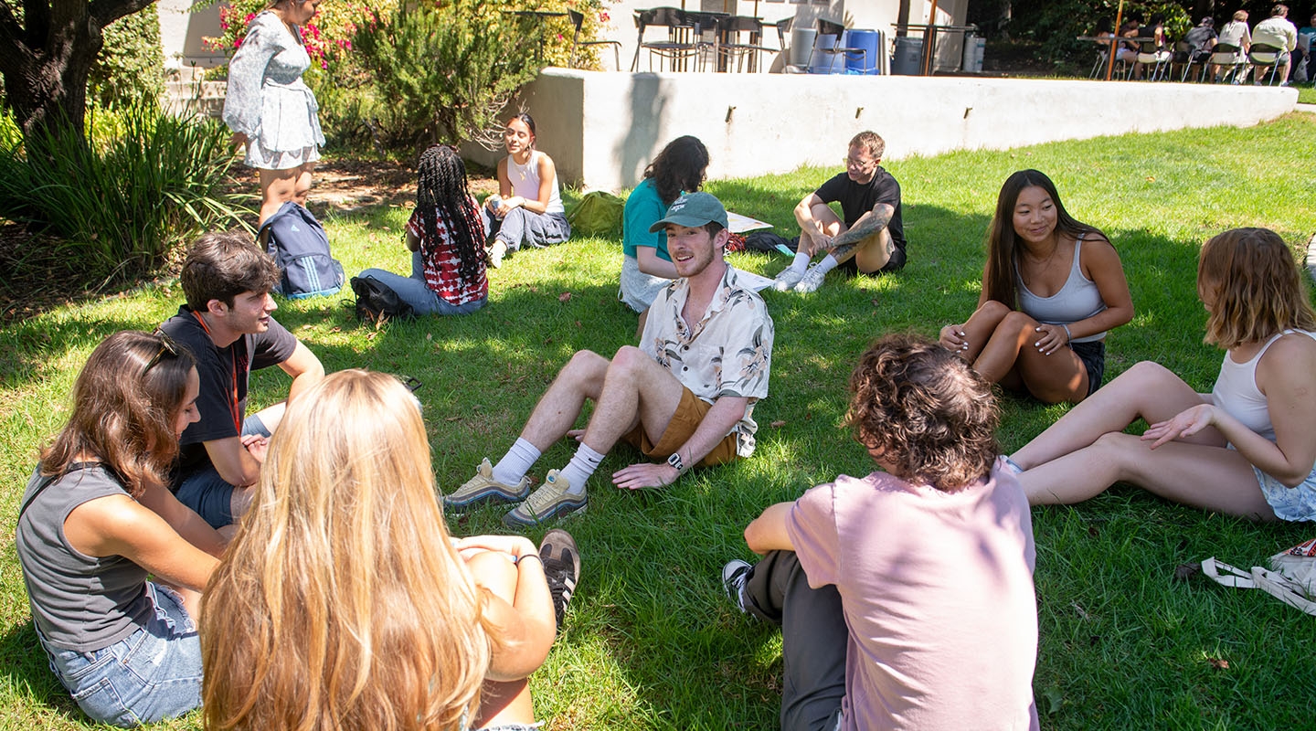 Occidental College students spread out on a green lawn, talking and smiling