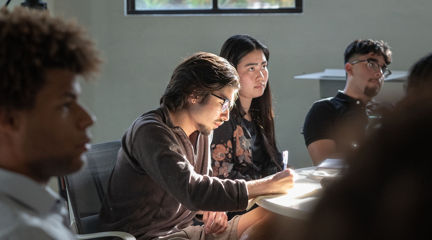 a group of Occidental College students in a classroom, with a male in the center bathed in sunlight