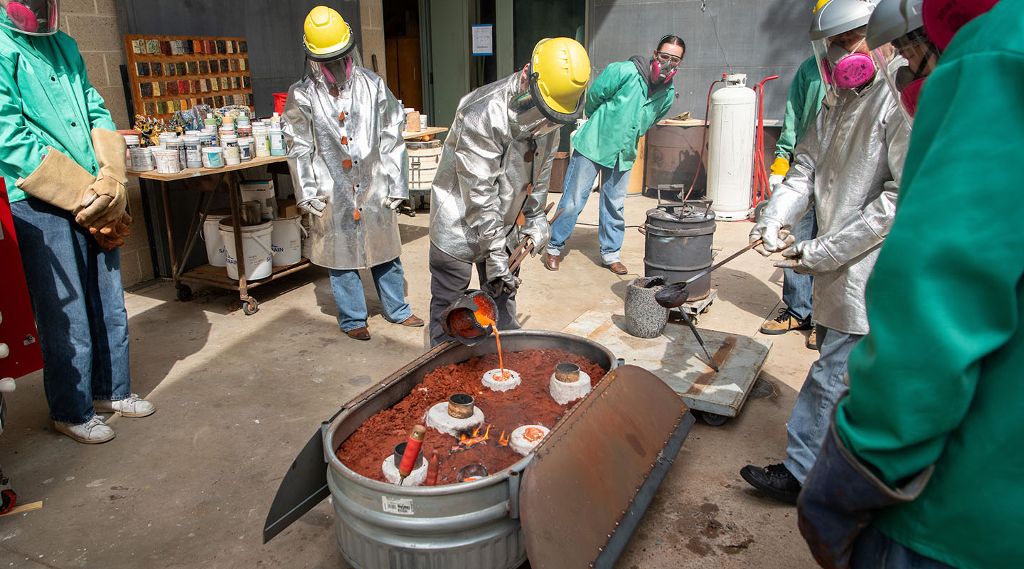 Oxy students in the courtyard by the art studio, using liquid metal to create sculptures