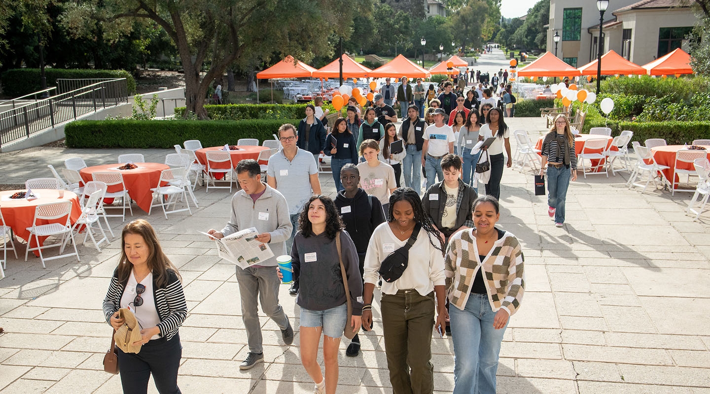 Prospective students and families walking across the Occidental College campus toward Thorne Hall