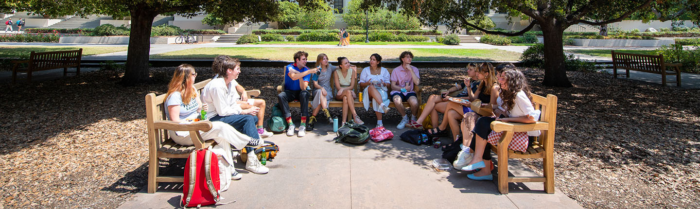 A group of Oxy students lined up on three benches facing each other on the Quad