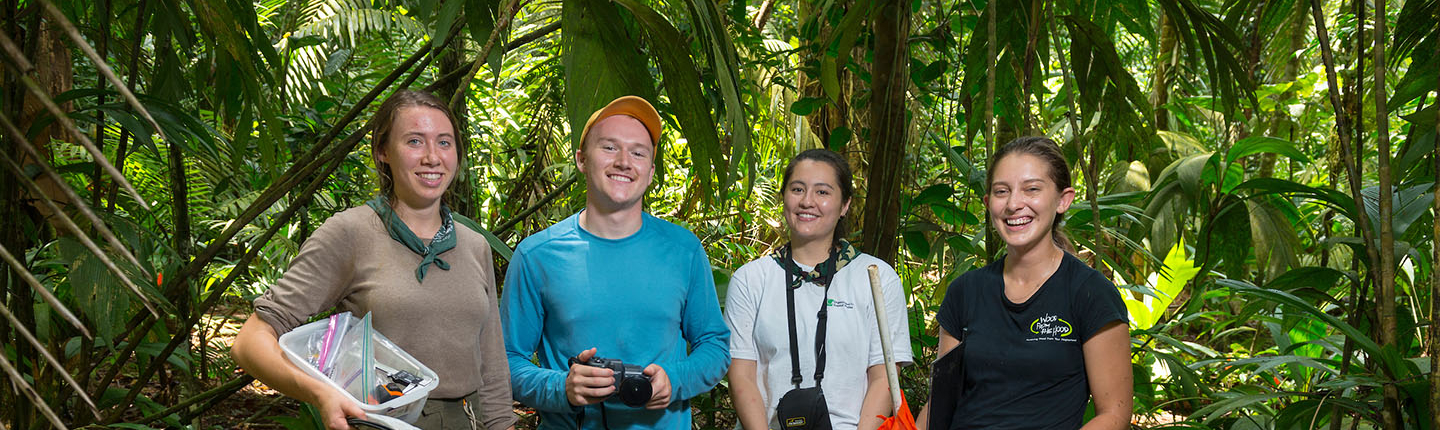 A group of four Occidental College students in the jungle of Costa Rica, standing together smiling