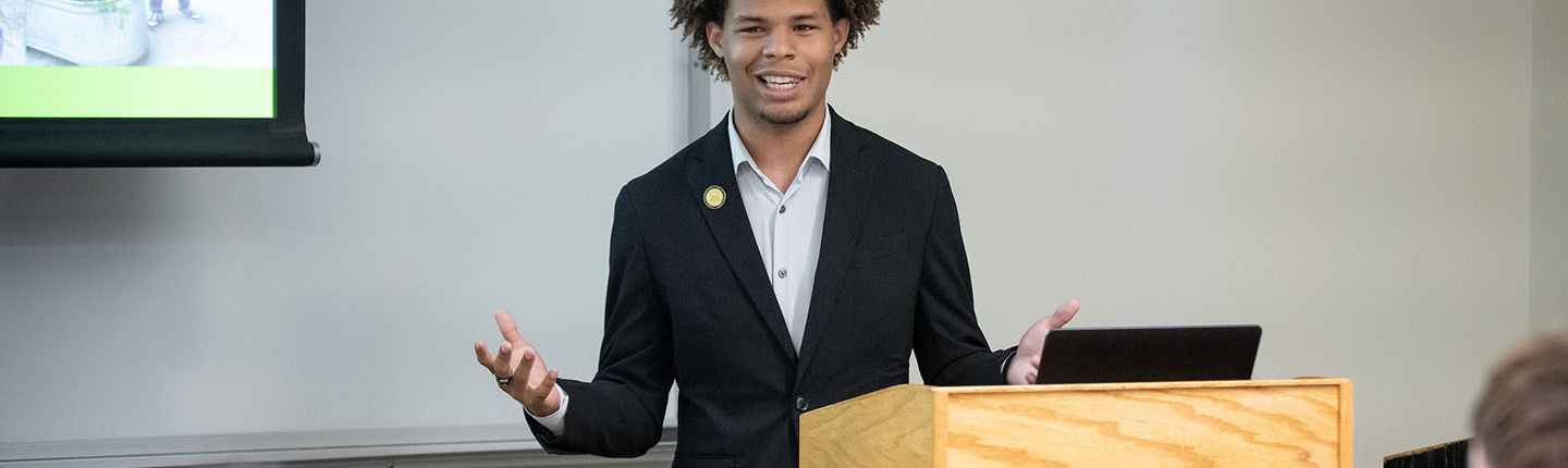 Jaymes Griggs presenting at a lectern at the Summer Research Program conference on the Occidental campus.