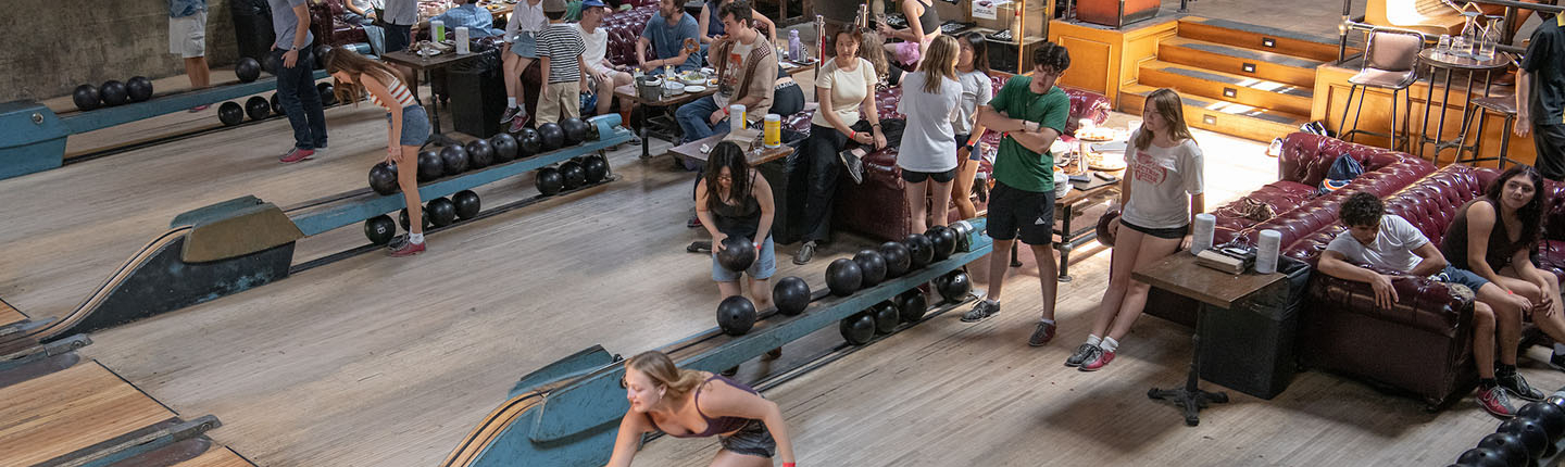 A large group of students bowling at a steampunk-themed bowling alley