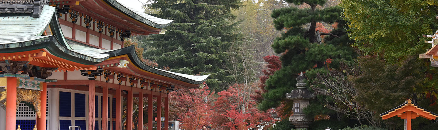 A view of the red Hiroshima temple with pine trees in the background