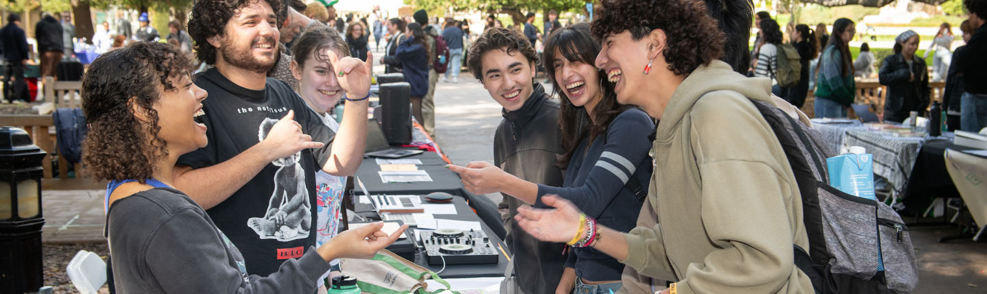 oxy students at a table at the involvement fair on the quad smiling and laughing