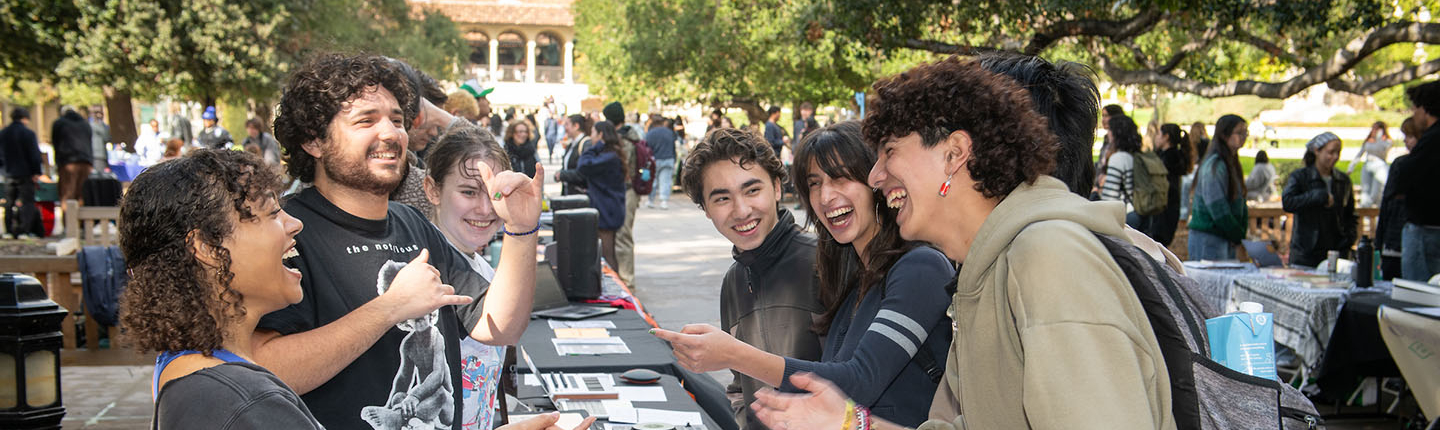 oxy students at a table at the involvement fair on the quad smiling and laughing