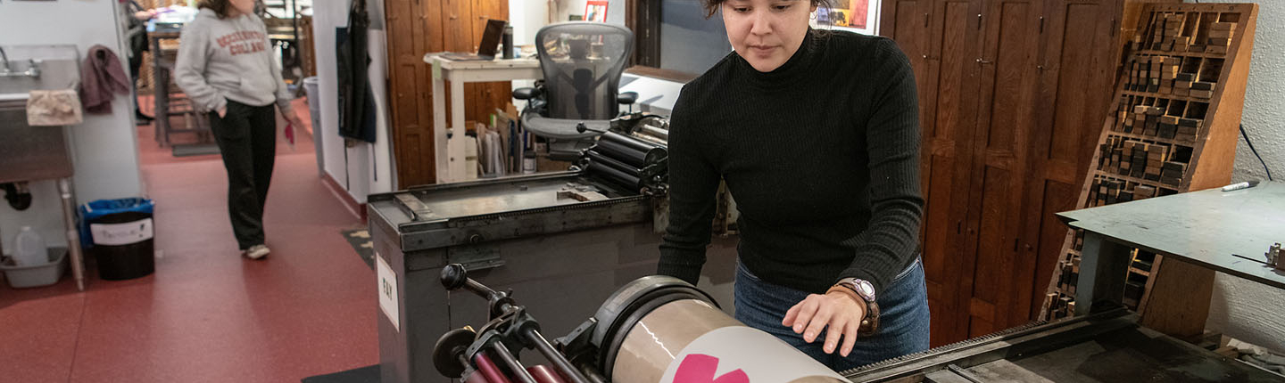 An Occidental College student printing a card at the Lowercase letterpress print shop in the library on campus
