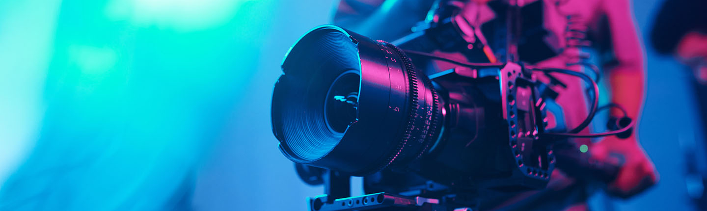 a cameraman holding a film camera with a colored background
