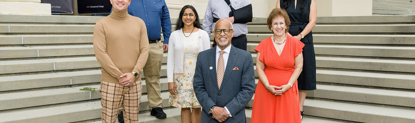 A group of alumni and President Elam stand in formation on some steps