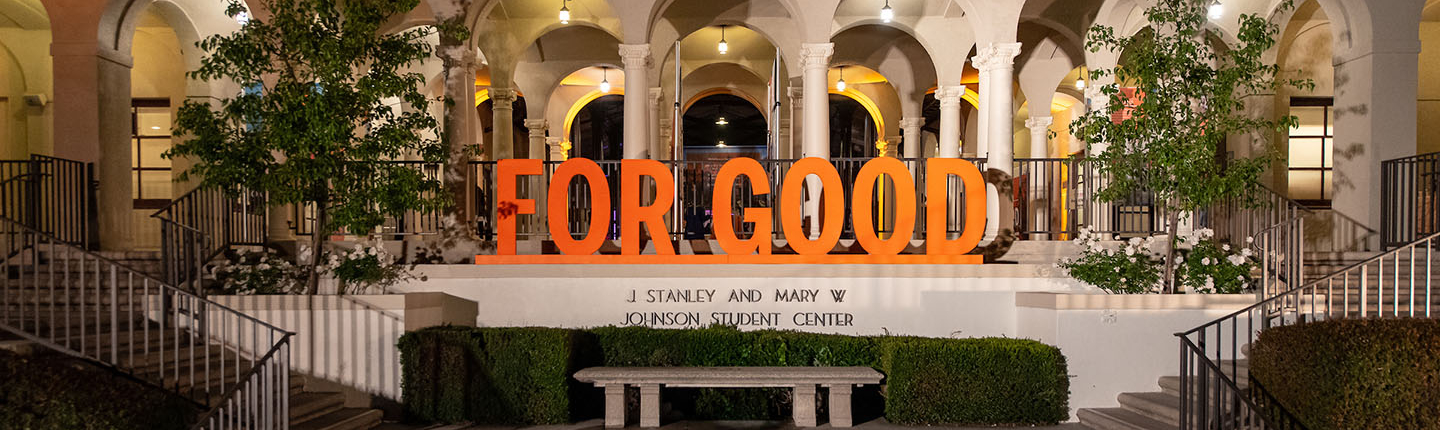 A shot of the Johnson Student Center south entrance with a fountain and the 3-D letters For Good assembled