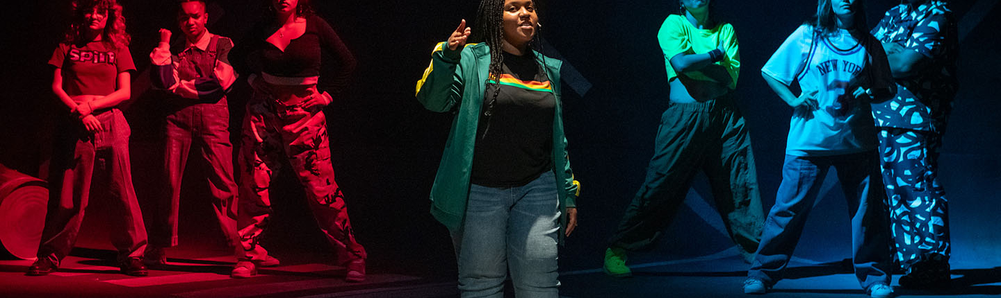 students in hip-hop clothing stand in a formation on the Keck Theater stage