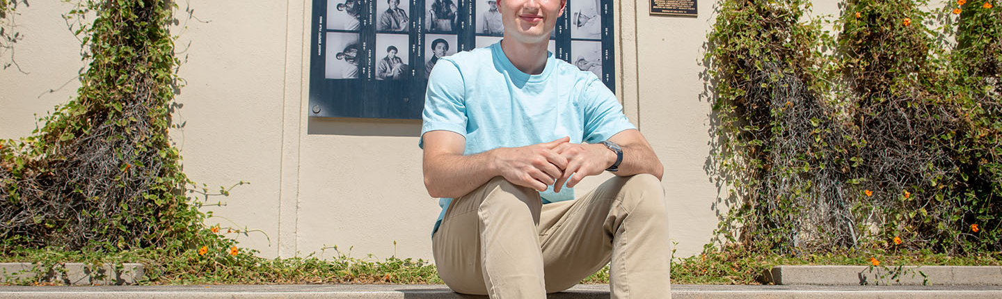 James Steinberger '25 sits on the steps in front of Haines Hall with a blue shirt.